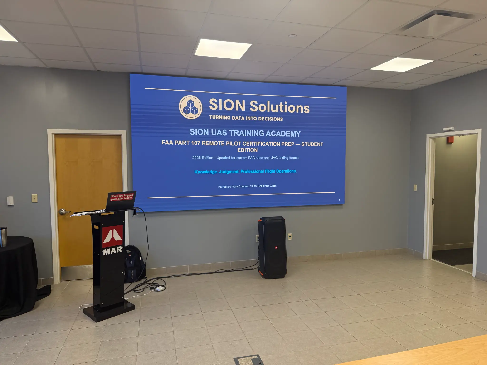 Ivory Cooper at the front of the Byhalia classroom beside a SION Solutions UAS Training Academy opening slide